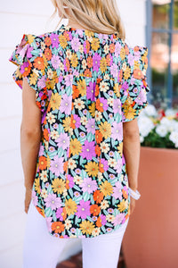 Black blouse with floral print Vibrant color infusion Ruffled sleeves Unique style statement Whimsical fashion